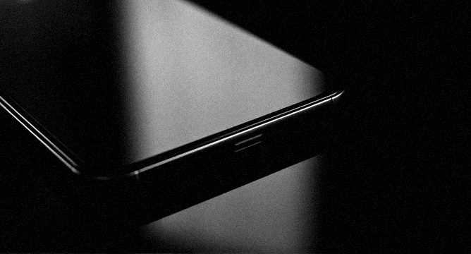 A phone edge lit on black glass